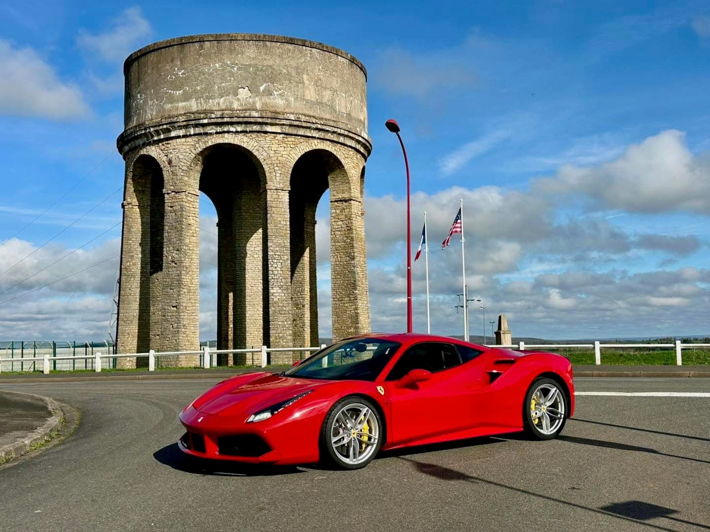 Ferrari 488 rouge vue trois-quarts avant devant la tour d'eau près du circuit de Magny-Cours, carrosserie intégralement protégée par film XPEL posé par AWD Magny-Cours
